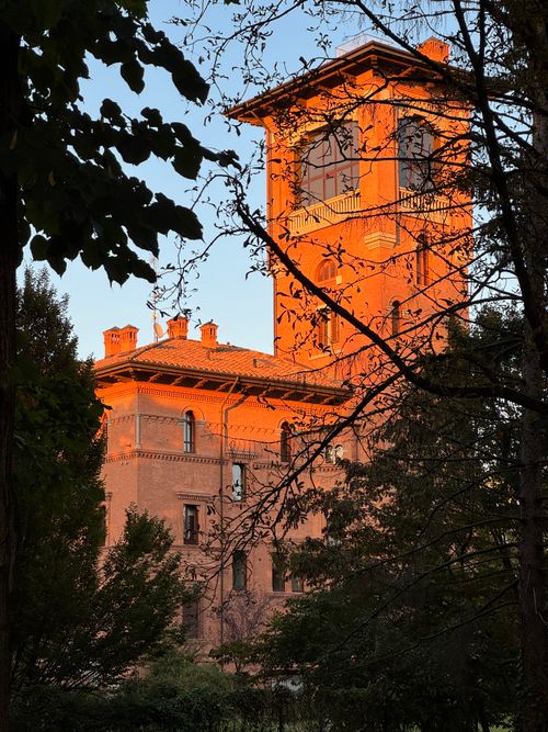 Free Majestic Spilamberto tower illuminated by sunset, surrounded by trees, capturing Italy's architectural charm. Stock Photo