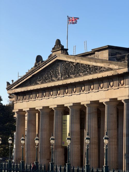 Free Neoclassical building in Edinburgh, Scotland, with Union Jack flag atop in sunny daylight. Stock Photo
