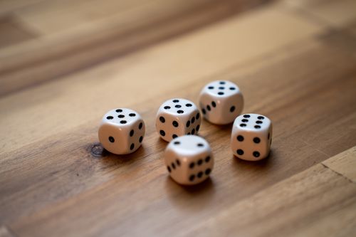 Free Close-up of five white dice with black dots on a wooden surface. Stock Photo