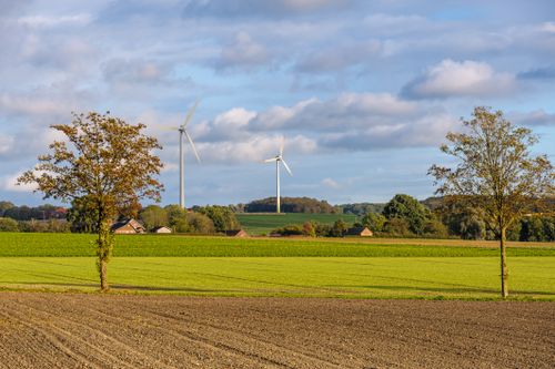 Free Beautiful rural scene in Coesfeld with green fields and wind turbines under a blue sky. Stock Photo
