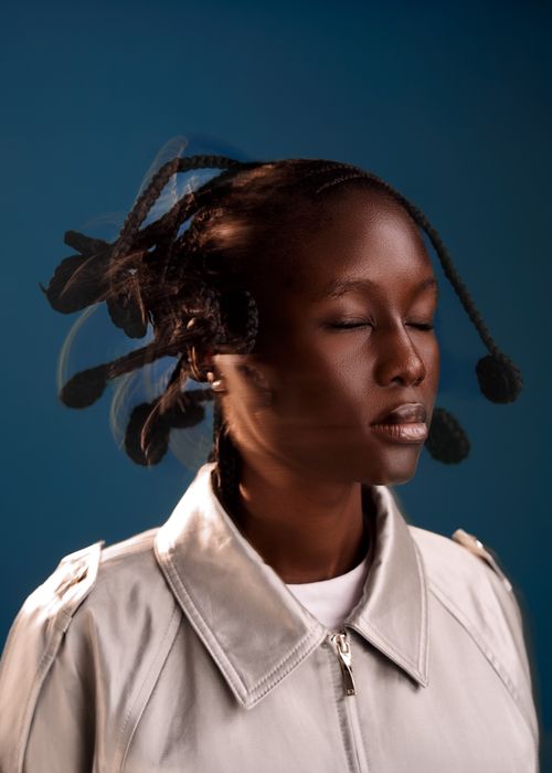Free Elegant portrait of a woman with artistic braids, eyes closed, against a blue backdrop. Stock Photo