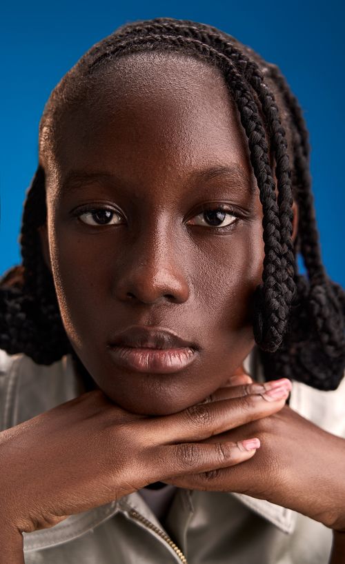 Free Close-up portrait of a young girl with braided hair resting her chin on her hands. Stock Photo
