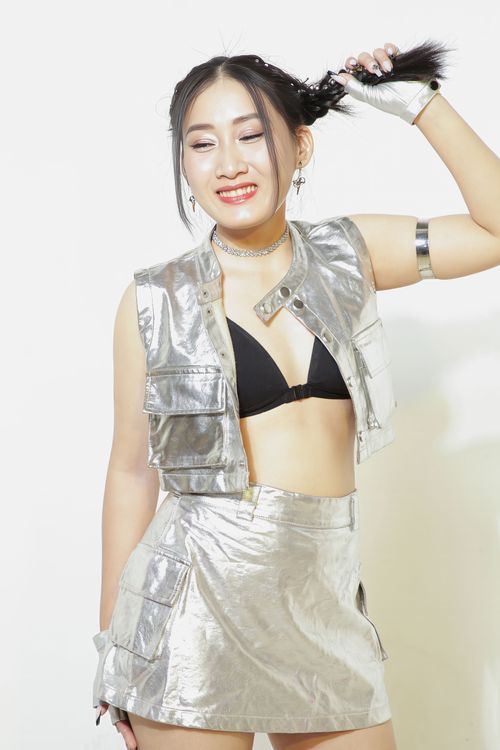 Free Stylish woman smiling in a metallic outfit, expressing joy and fashion-forward style. Stock Photo