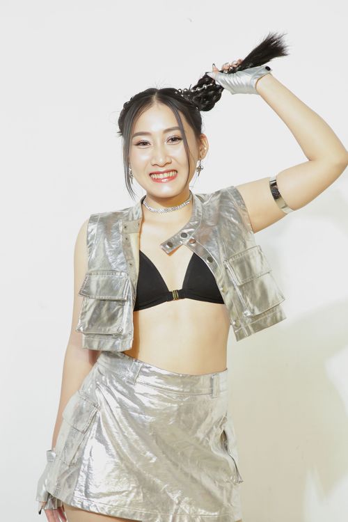 Free Smiling Asian woman posing in a stylish metallic outfit against a plain background. Stock Photo