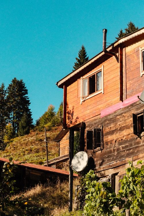 Free Charming wooden cabin in a mountainous landscape under a clear blue sky. Stock Photo