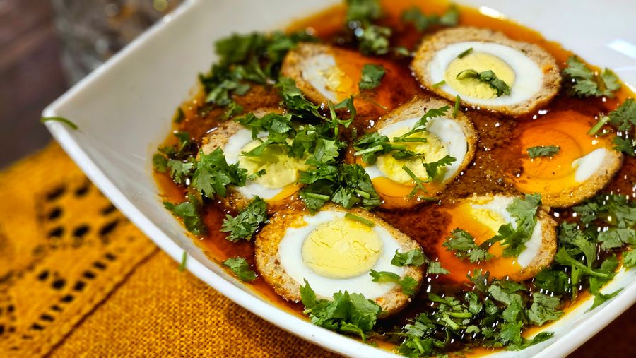 Spicy egg curry garnished with coriander in a white bowl