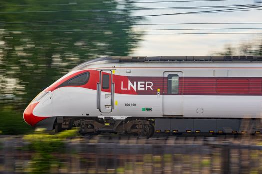 LNER train speeding through greenery, showcasing modern rail travel.