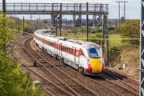 Free A sleek LNER Azuma train speeding along outdoor railway tracks in the UK countryside. Stock Photo