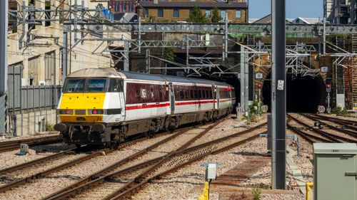 Free A high-speed train exits a tunnel in a busy city railway scene. Stock Photo