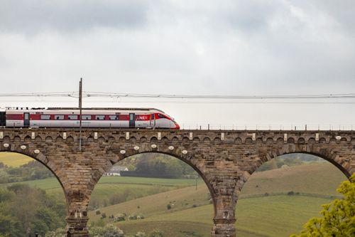 Free LNER train traveling over historic viaduct in scenic British countryside. Stock Photo