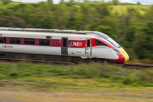 Free LNER Azuma train speeding through a lush countryside landscape, showcasing modern rail travel. Stock Photo