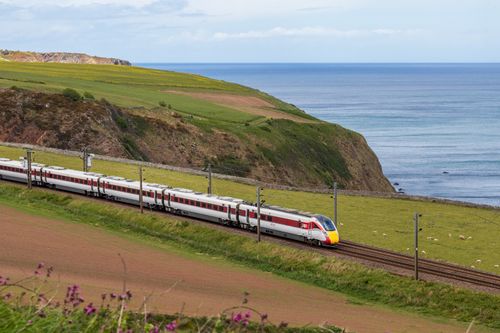 Free A high-speed train travels along a picturesque coastal landscape with cliffs and ocean views. Stock Photo