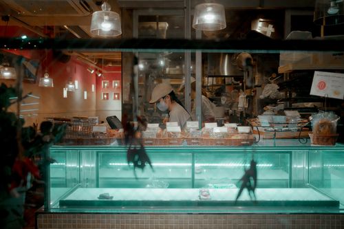 Free A bakery display with a pastry chef working inside, creating an inviting, warm atmosphere. Stock Photo