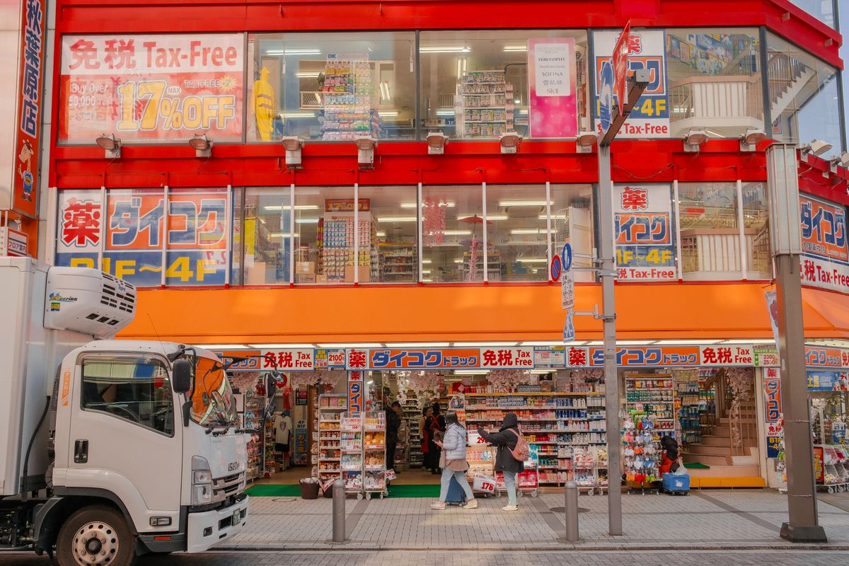 Japanese drugstore with a red Tax-Free sign above the entrance and shoppers on the sidewalk
