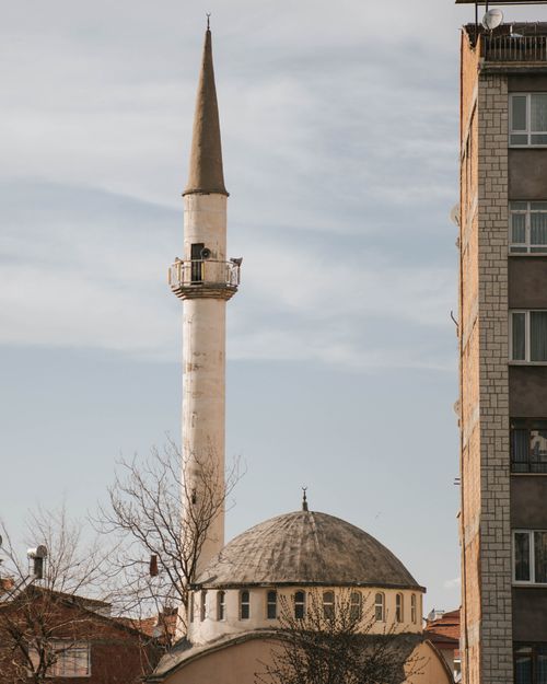 Free A minaret beside a modern building against a clear sky. Stock Photo