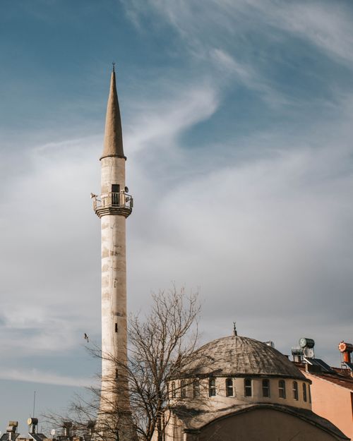 Free A tall mosque minaret under a bright blue sky with scattered clouds, showcasing Islamic architecture. Stock Photo