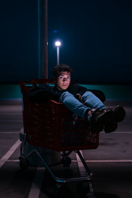 A Man Sitting on a Shopping Cart