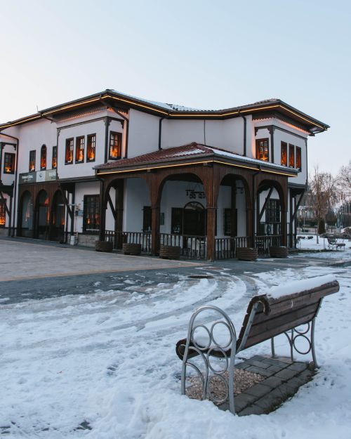Free A charming historic building with wooden accents stands amidst winter snow, captured during twilight. Stock Photo