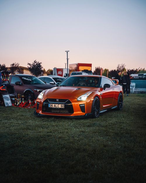 Free A striking orange sports car parked outdoors during sunset at a car show in Ankara, Türkiye. Stock Photo