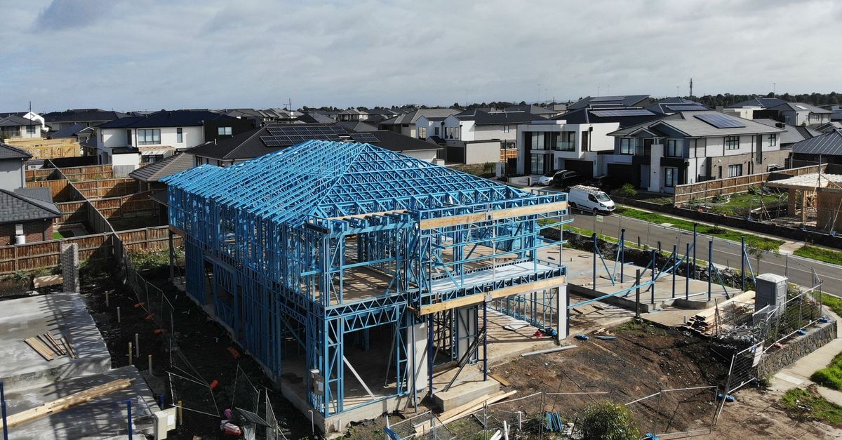 Aerial view of a contemporary house under construction, featuring a blue steel framework.