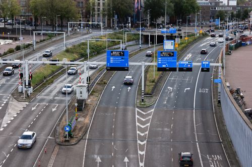 Free Overview of bustling Amsterdam intersection showing traffic flow and signage. Stock Photo