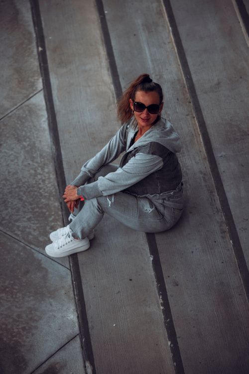 Free Woman in casual attire seated on urban pavement, showcasing modern lifestyle in St. Petersburg, Florida. Stock Photo