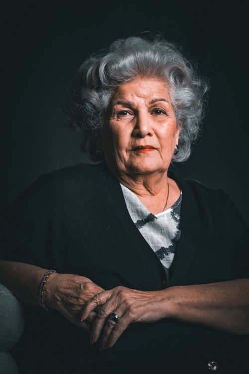 Free Vibrant portrait of a senior woman with gray hair against a dark background. Stock Photo