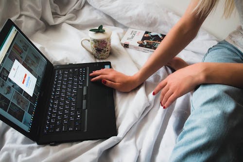 Free 
A Woman Using a Laptop in Bed Stock Photo