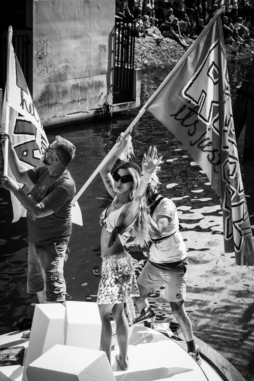 Free Black and white scene of people celebrating with flags on a boat in Amsterdam canal. Stock Photo
