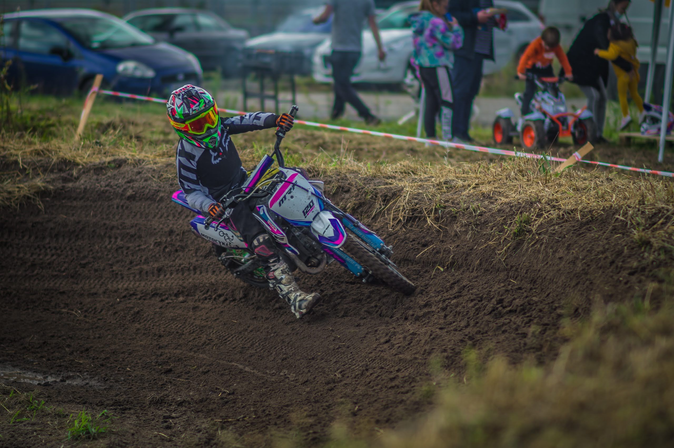 Child motorcyclist on dirt track with blurred spectators