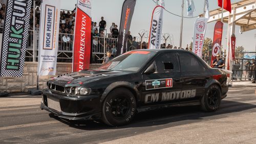 Free Black race car preparing at an outdoor racing event with spectators in the background. Stock Photo