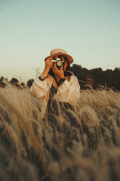 Unrecognizable female photographer taking photo on camera in field