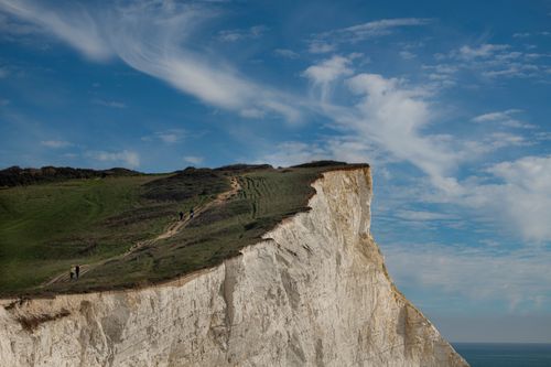 Free Breathtaking view of Seaford Head cliffs with hikers under a vivid blue sky. Stock Photo