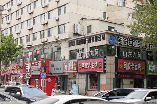 Lively street view featuring shops and traffic in a Chinese city, highlighting urban life and architecture.