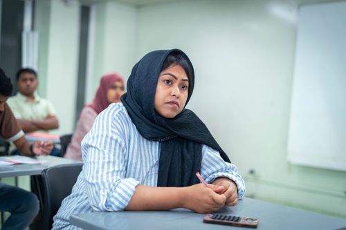 Free A student attentively taking notes in an educational setting, showcasing active learning. Stock Photo