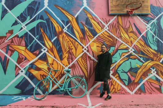 Colorful street art background with a bicycle and a man smiling nearby.