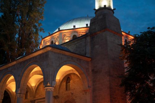 Free A beautifully lit mosque with arches and domes under the night sky in Pristina. Stock Photo