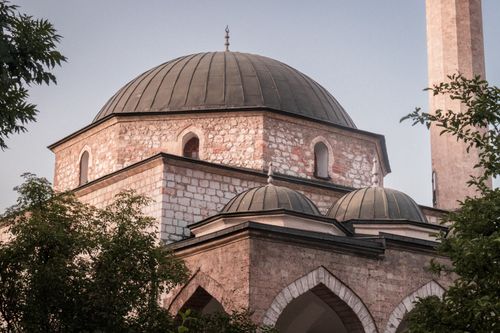 Free A beautiful exterior view of a historic mosque dome in Sarajevo, Bosnia, surrounded by greenery. Stock Photo