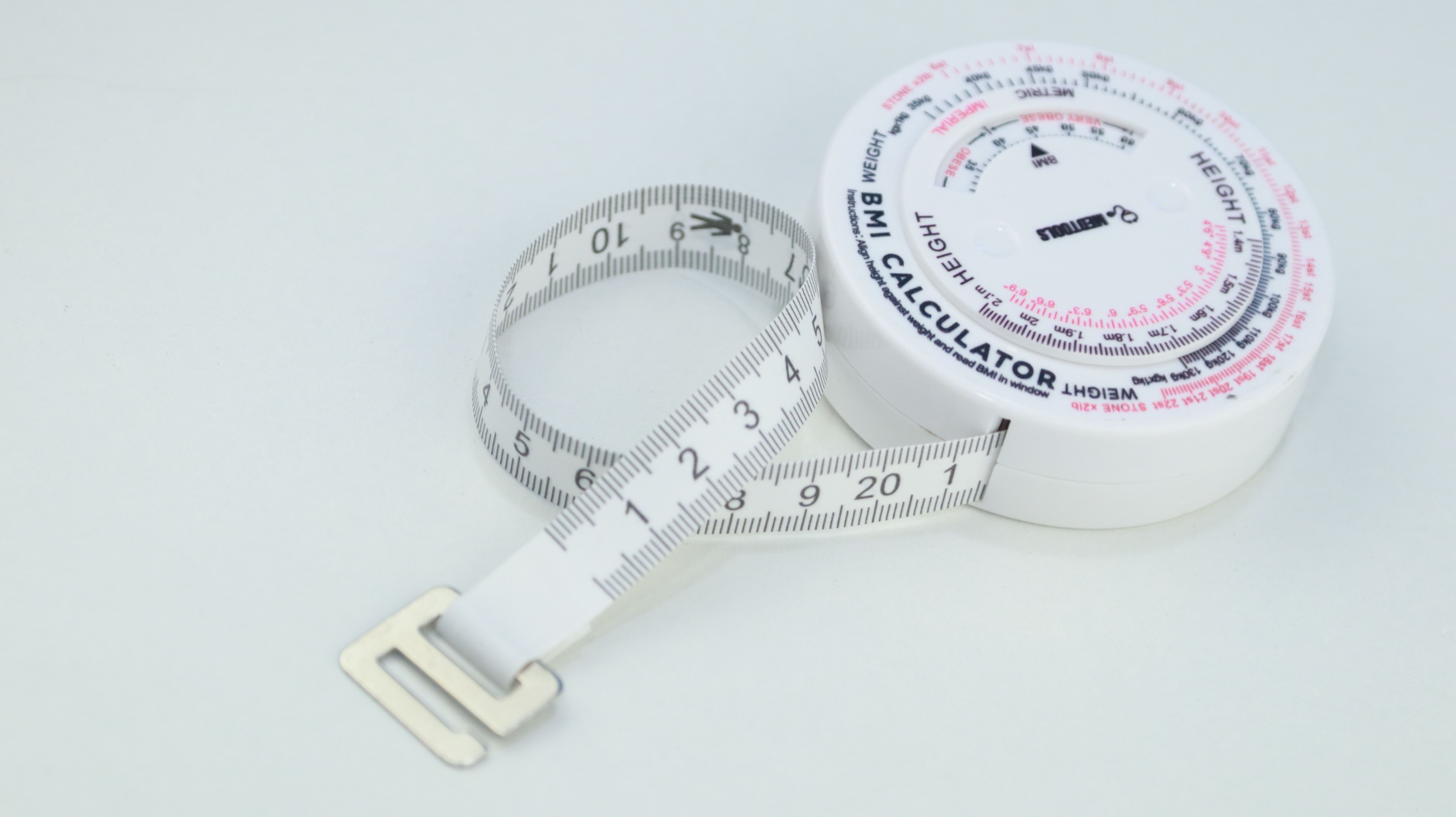 A BMI calculator and measuring tape on a white background, emphasizes health and wellness.