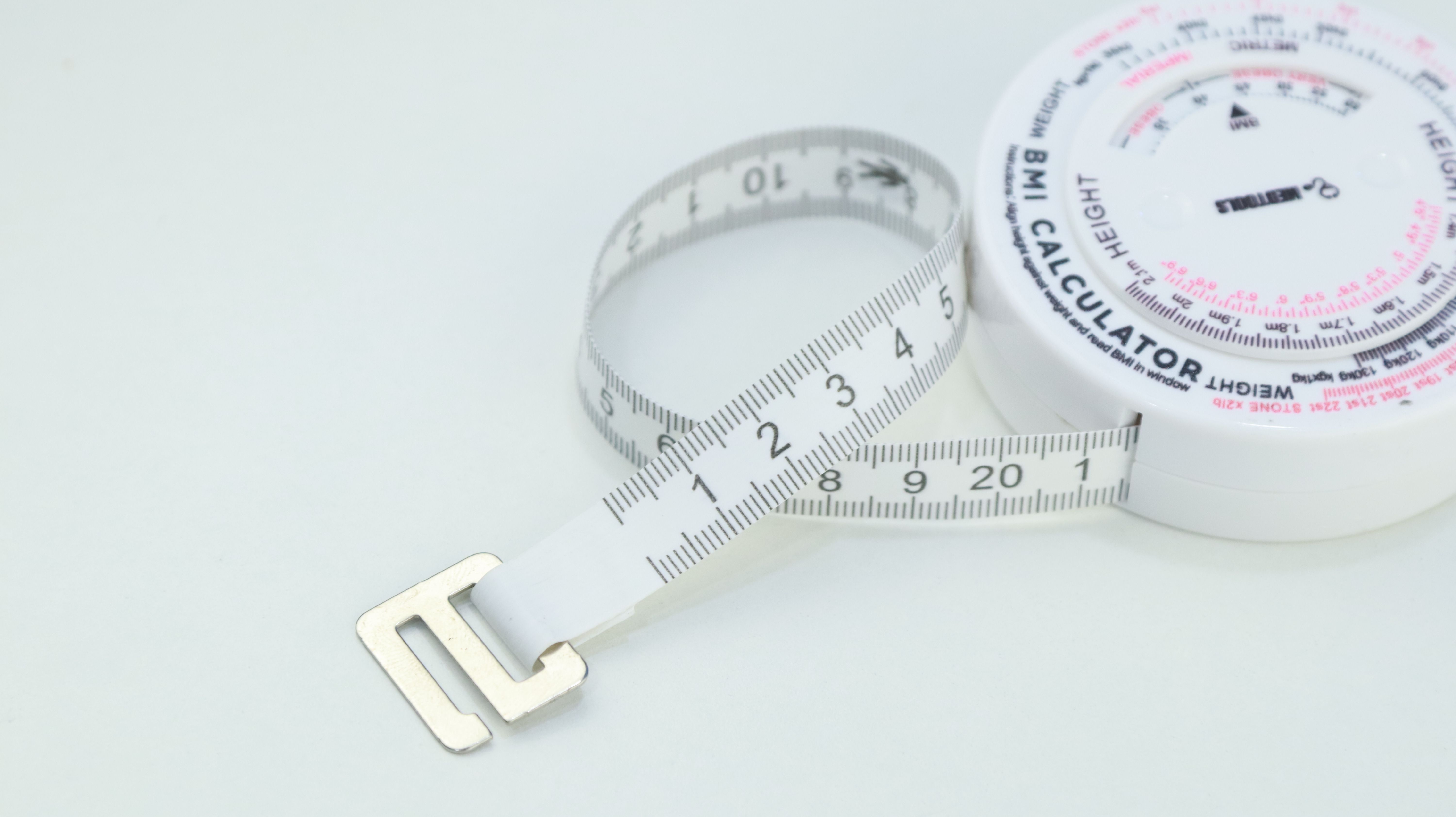 Close-up of a BMI calculator and measuring tape, essential for health assessments.