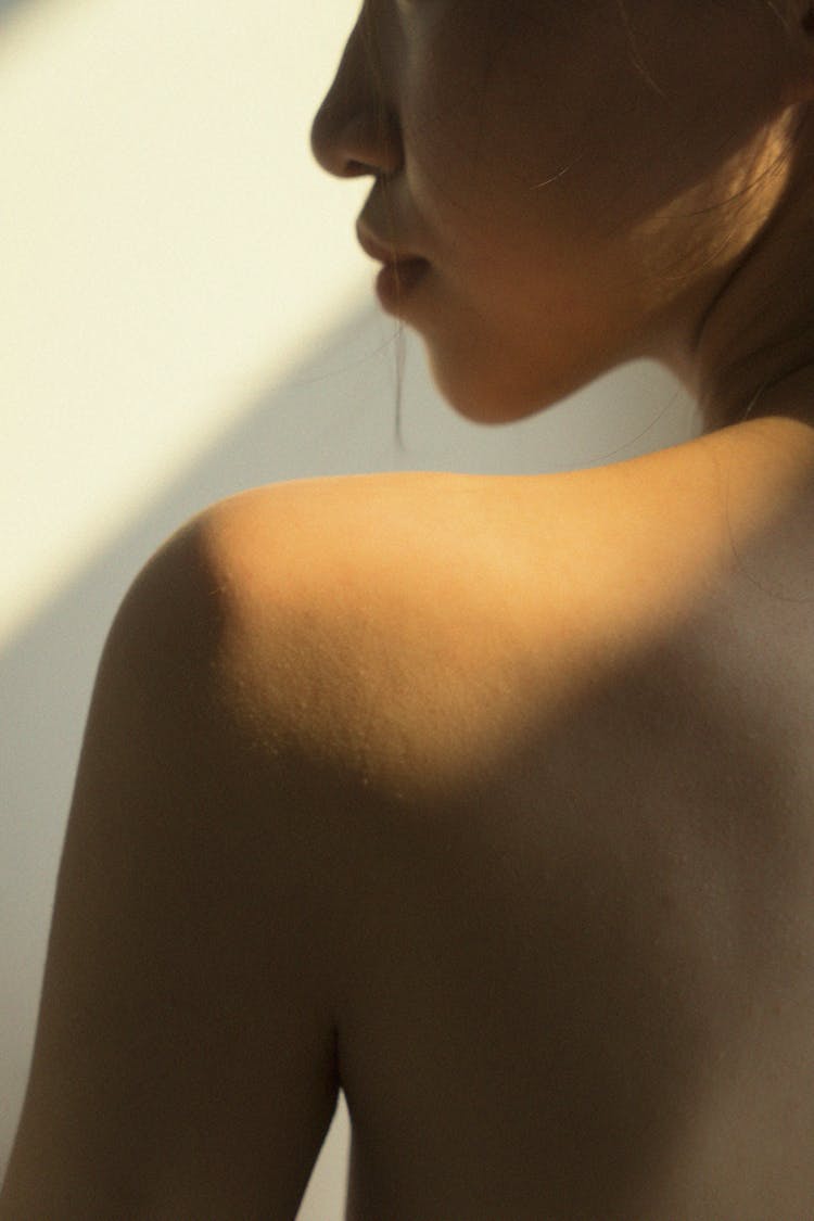 Topless Woman Standing Near White Wall