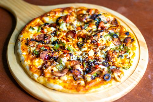 Free Close-up of a freshly baked pepperoni pizza with colorful toppings on a wooden board. Stock Photo