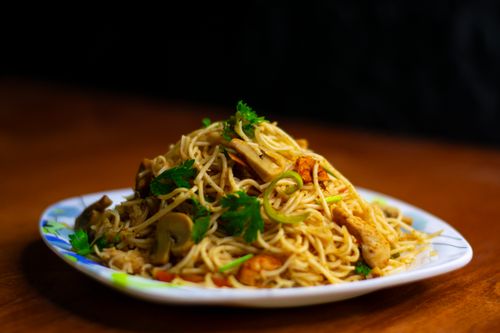Free Tasty spaghetti dish garnished with mushrooms and herbs, served on a colorful plate. Stock Photo