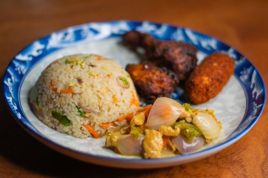 Plate of chicken fried rice, fried chicken, and vegetables captured in a vibrant setting.