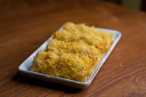 Free A close-up of golden fried snacks on a rectangular white plate on a wooden table. Stock Photo