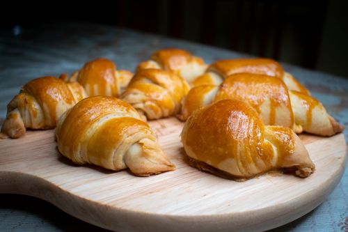 Free Golden brown croissants freshly baked, placed on a wooden board, ready to be served. Stock Photo