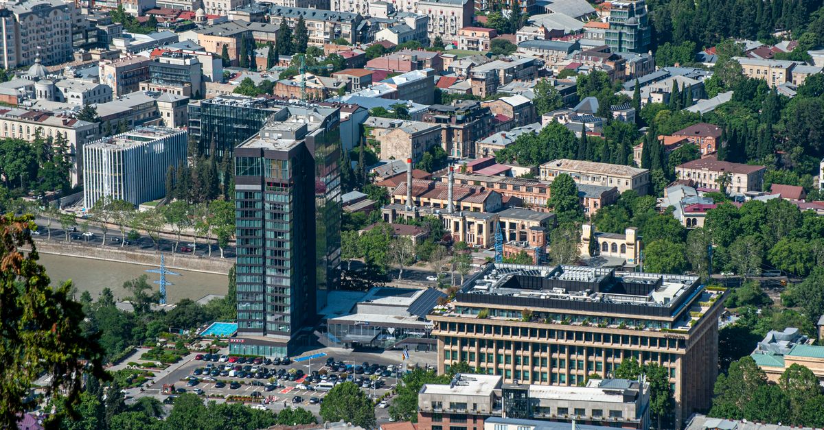Elevated view of Tbilisi cityscape with modern and historic buildings, showcasing vibrant urban life.