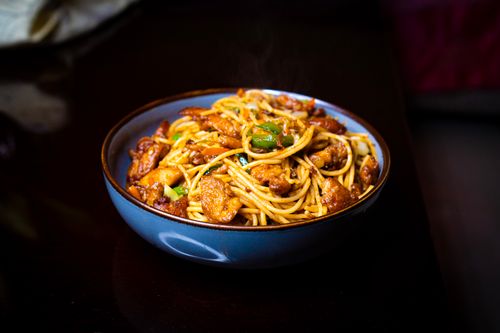 Free Freshly cooked chicken chow mein with vegetables in a blue bowl, ideal for food photography. Stock Photo
