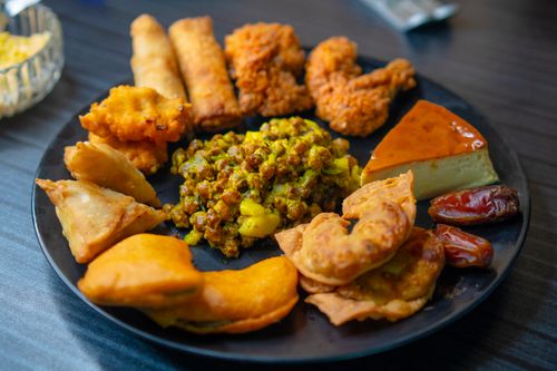 Free A vibrant platter of assorted Indian snacks and dessert neatly arranged on a black plate. Stock Photo