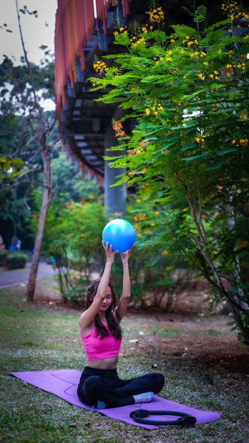 Free Woman practicing yoga with exercise ball in Jakarta park during the day. Stock Photo
